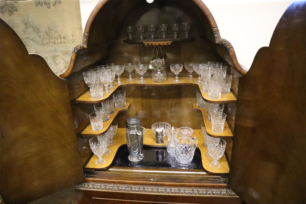 A burr walnut cocktail cabinet, width 81cm, depth 50cm, height 177cm with a collection of Tudor cut glassware